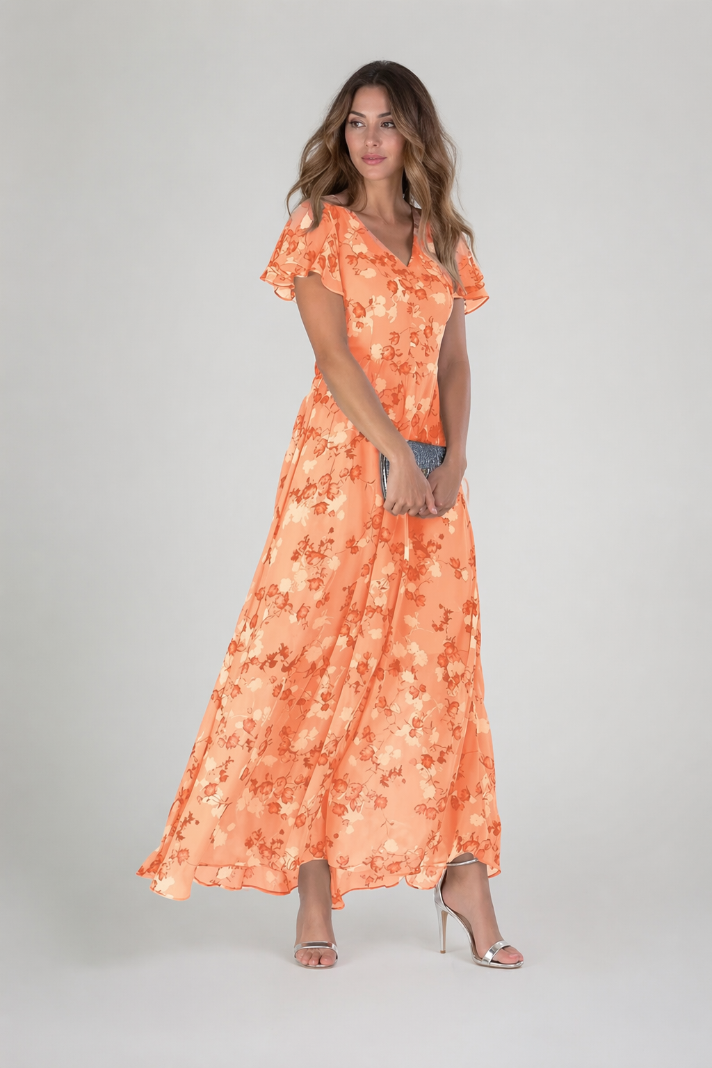 Woman wearing an orange floral dress on a gray background