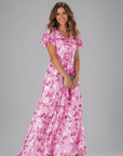 Woman wearing a pink floral dress on a gray background