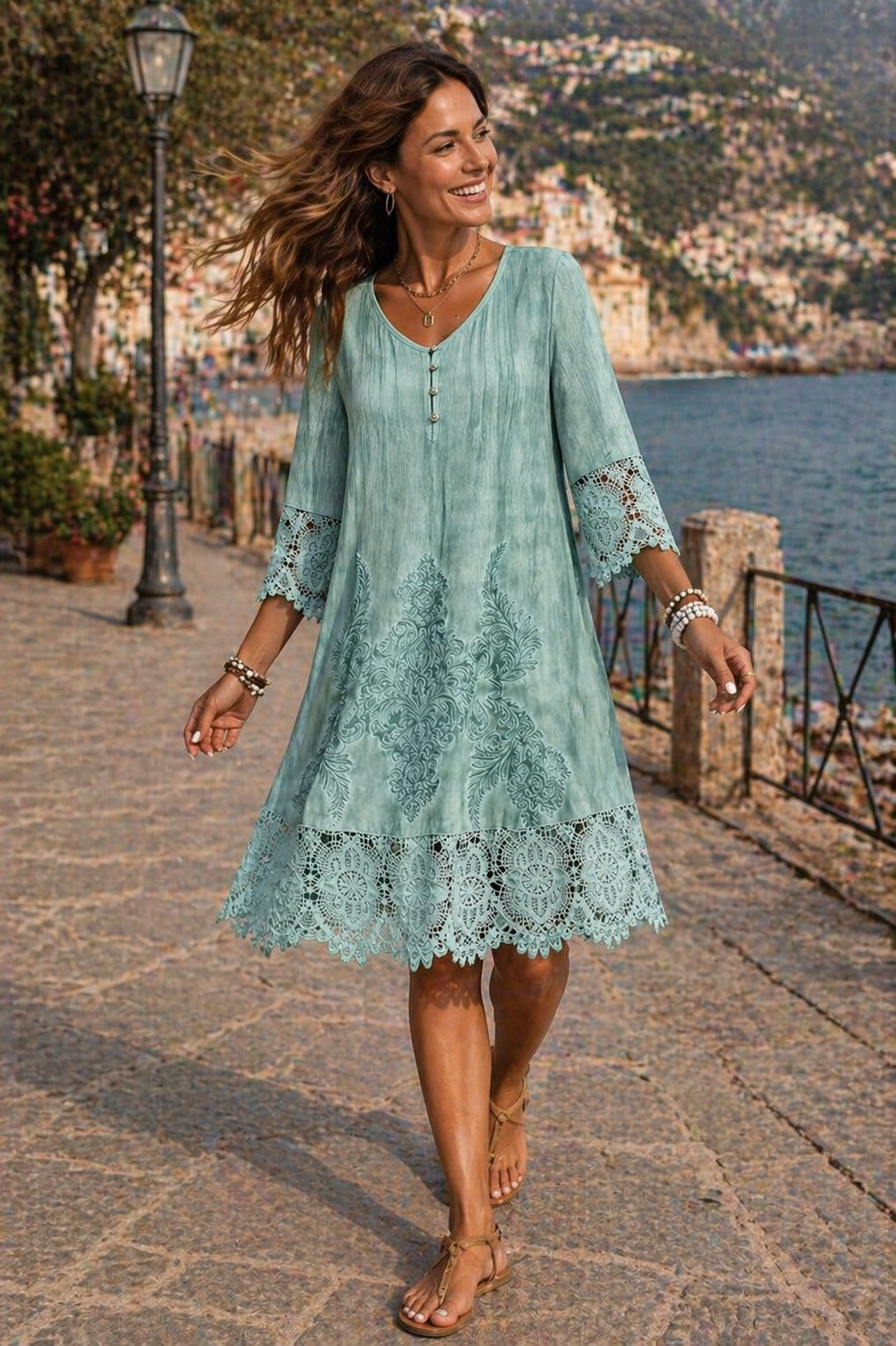 Woman in a light blue lace dress walking along a scenic coastal path.
