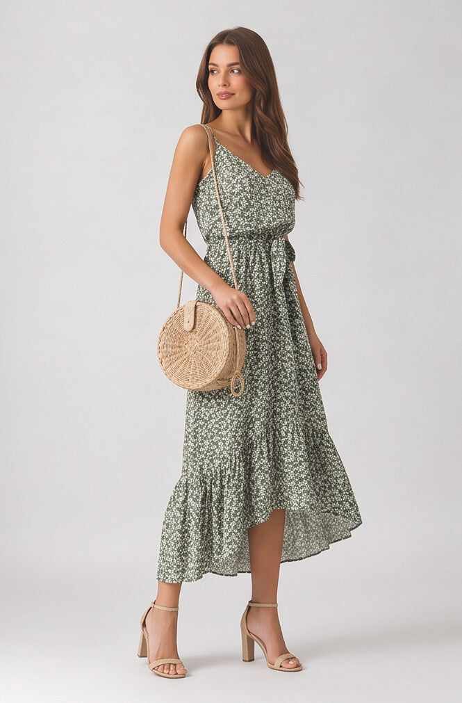Woman wearing a green floral dress holding a round beige bag on a white background